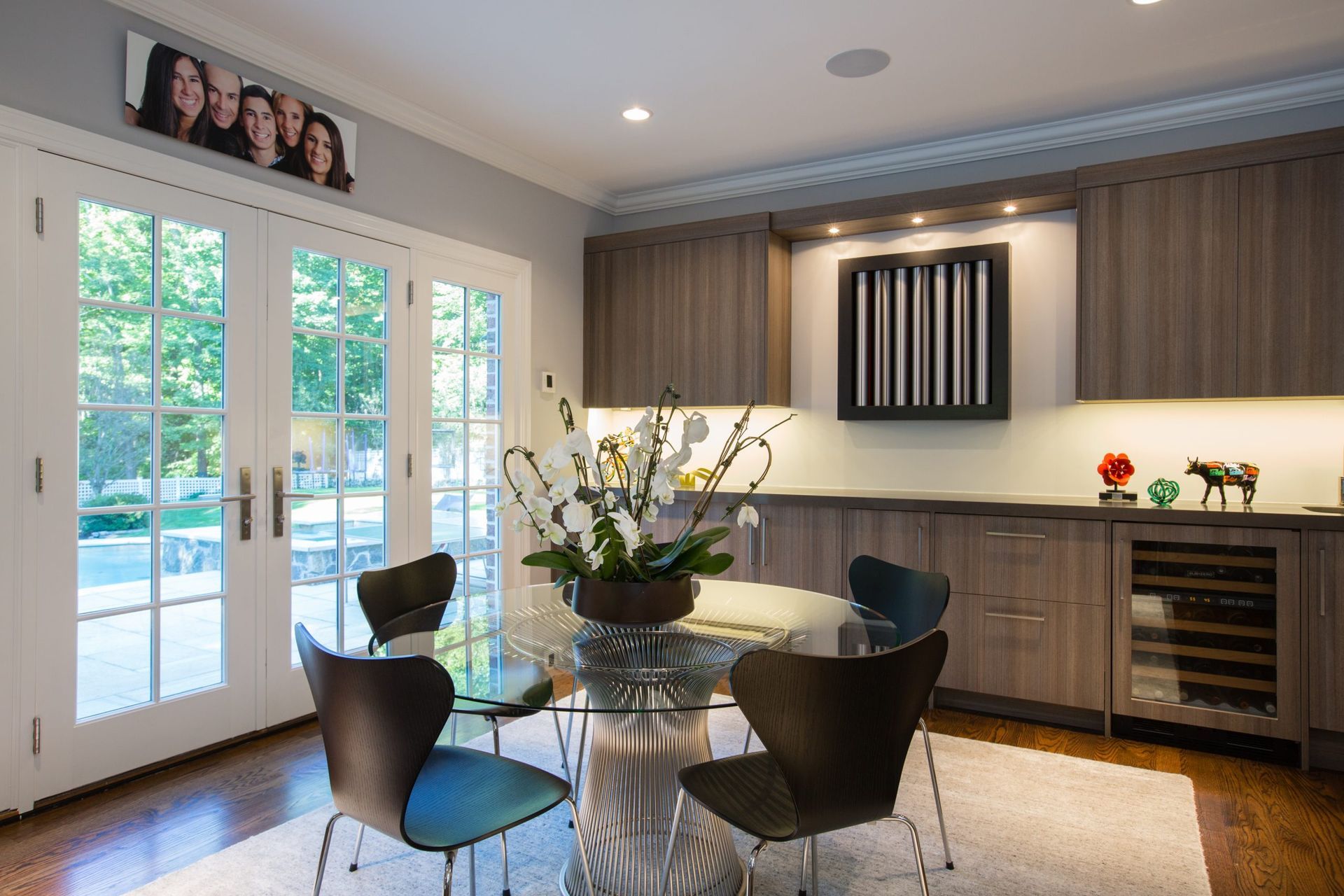 Dining room with a glass table, modern chairs, and cabinets. French doors lead outside.