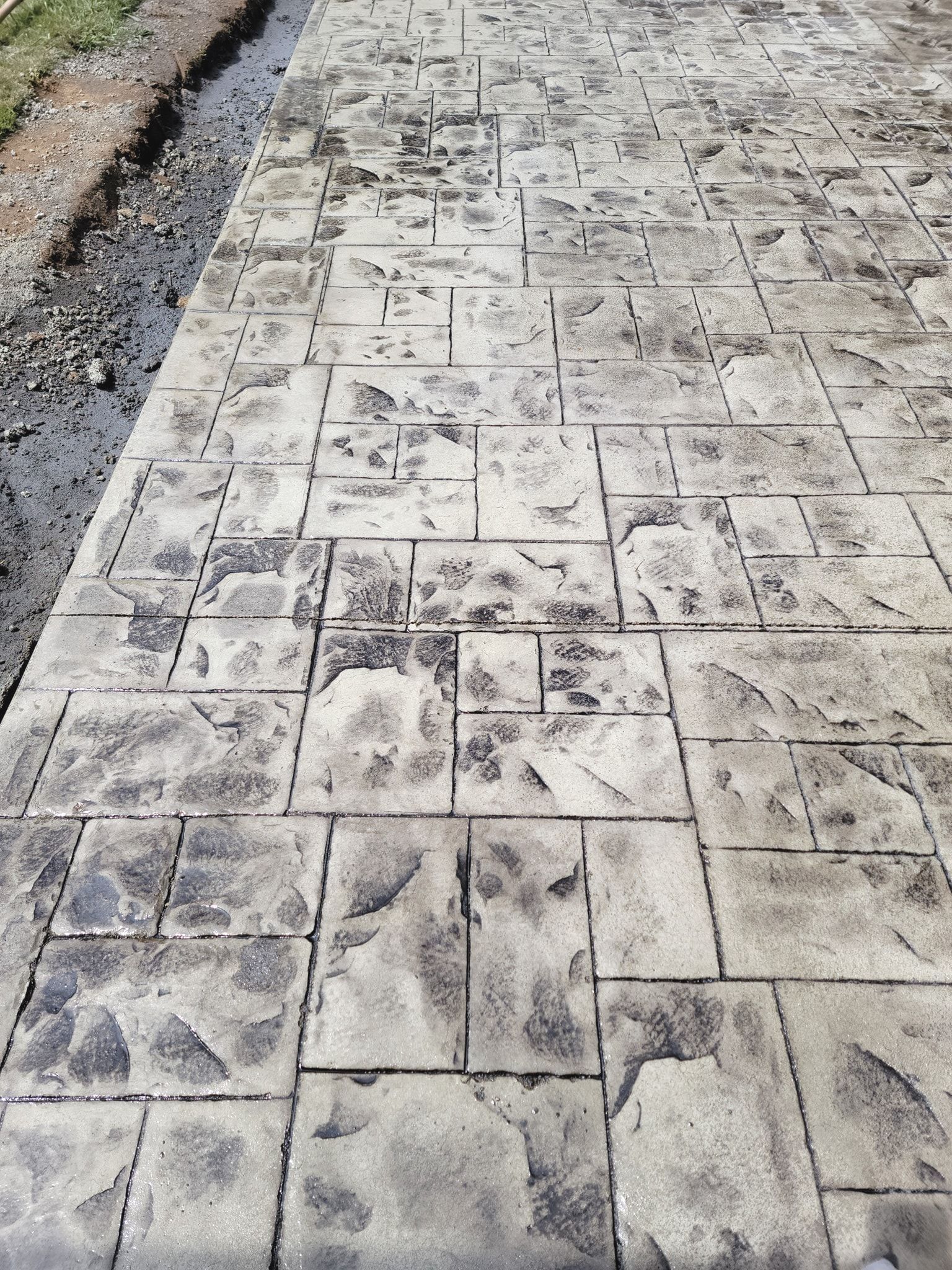 A close up of a concrete walkway with a brick pattern.