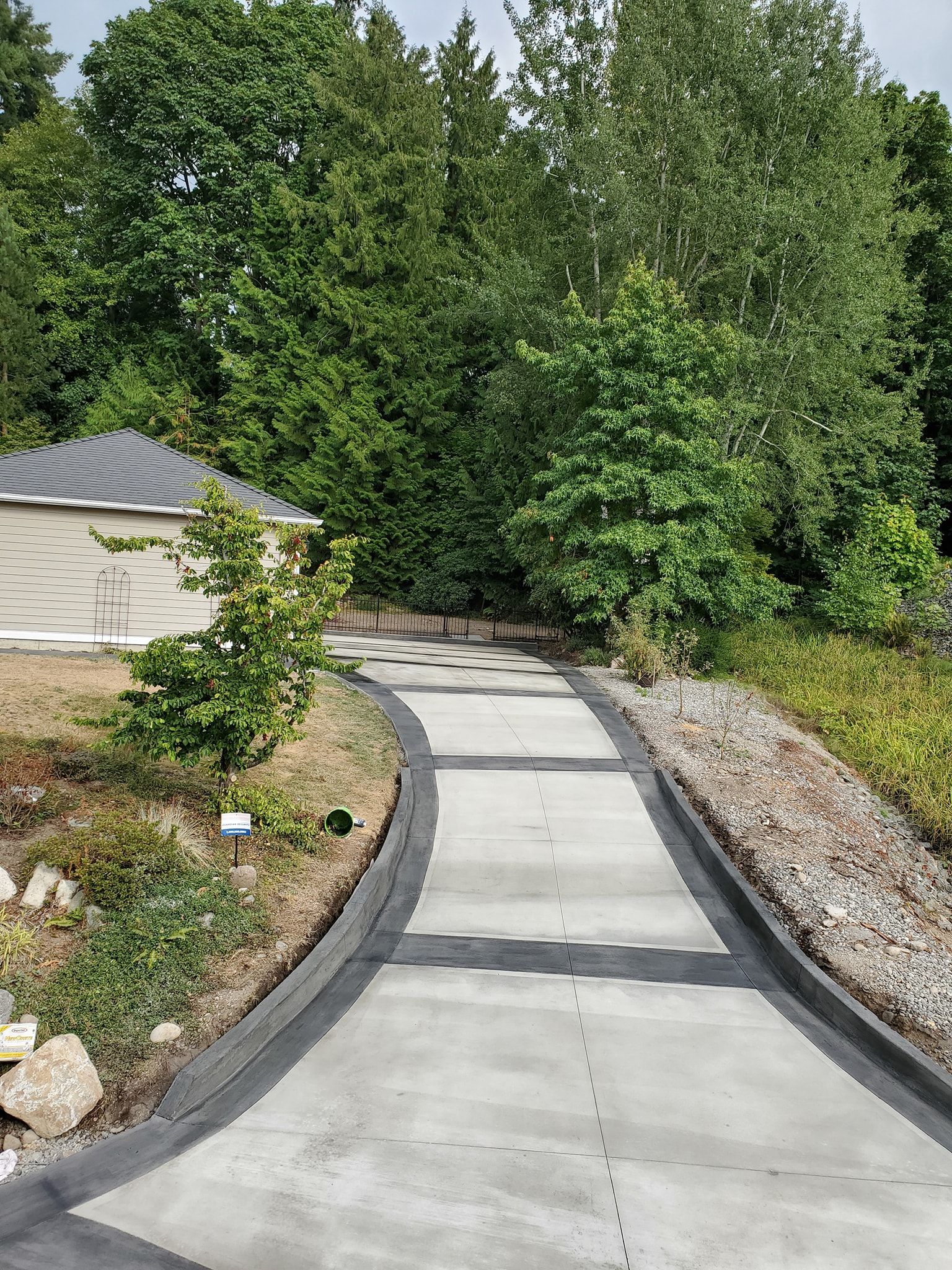 A concrete driveway leading to a house surrounded by trees.