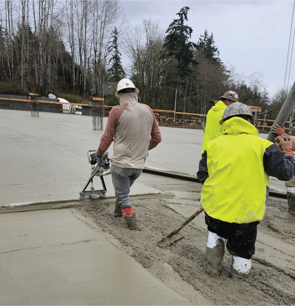 A group of construction workers are working on a concrete floor