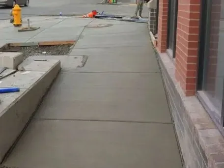 a concrete broom finished sidewalk is being built next to a retaining wall brick building in Bellingham Washington.