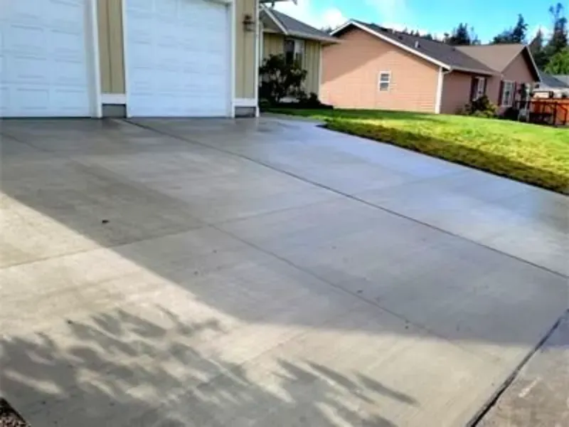 A concrete driveway leading to a house with two garage doors