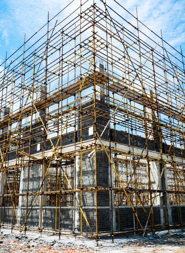 Scaffolding surrounds a building under construction; blue sky in background.