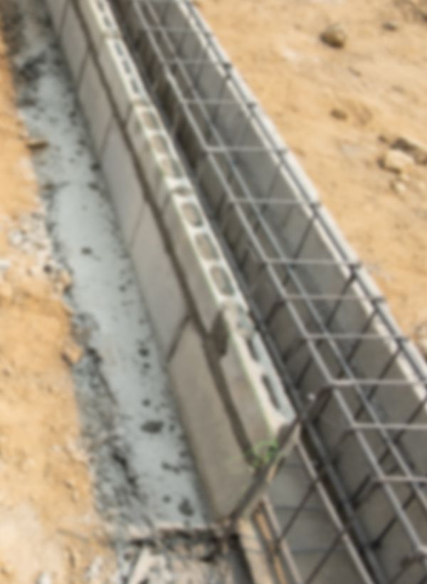 A row of concrete blocks for concrete foundation sitting on top of a dirt ground