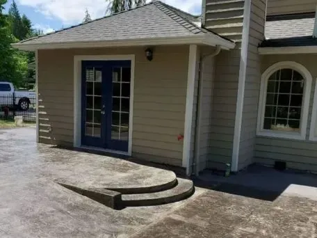 the front of a house with a blue door and stamped concrete patio with steps in Bellingham Washington.