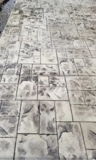 A close up of a concrete walkway with a brick pattern.