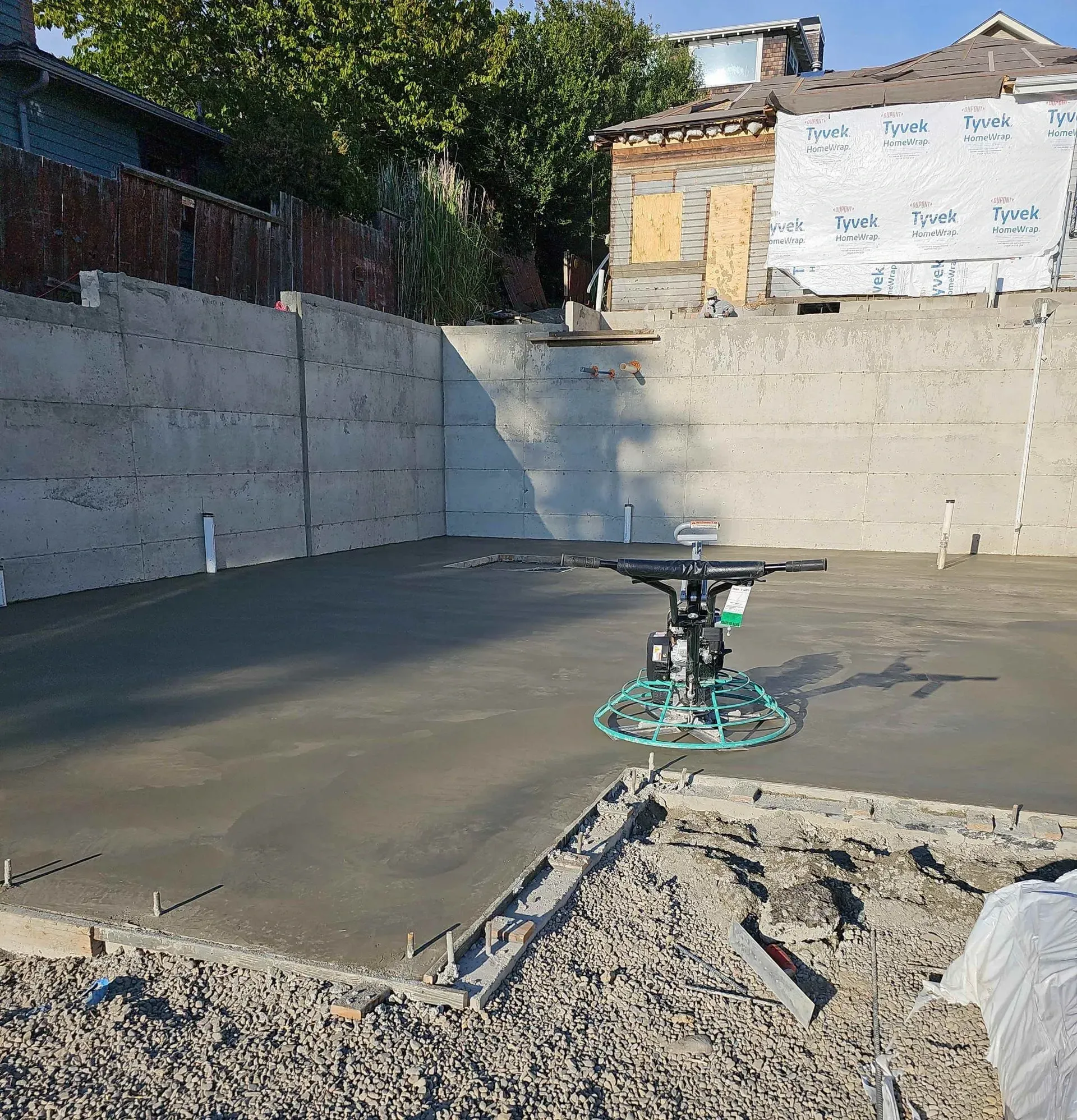 A concrete floor is being smoothed by a power trowel in a construction site.