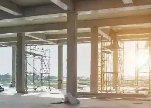 The sun is shining through the windows of a building under construction.