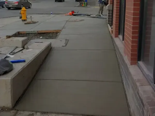 A sidewalk is being built in front of a brick building.