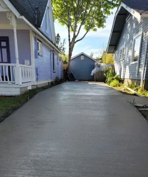 A concrete driveway leading to a purple house and a blue house.