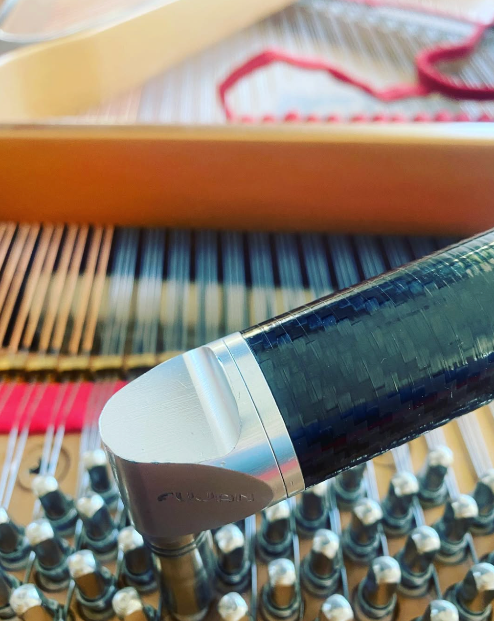 Close-up of a sushi roll being cut with a knife over a bamboo sushi mat and tray of rolls.