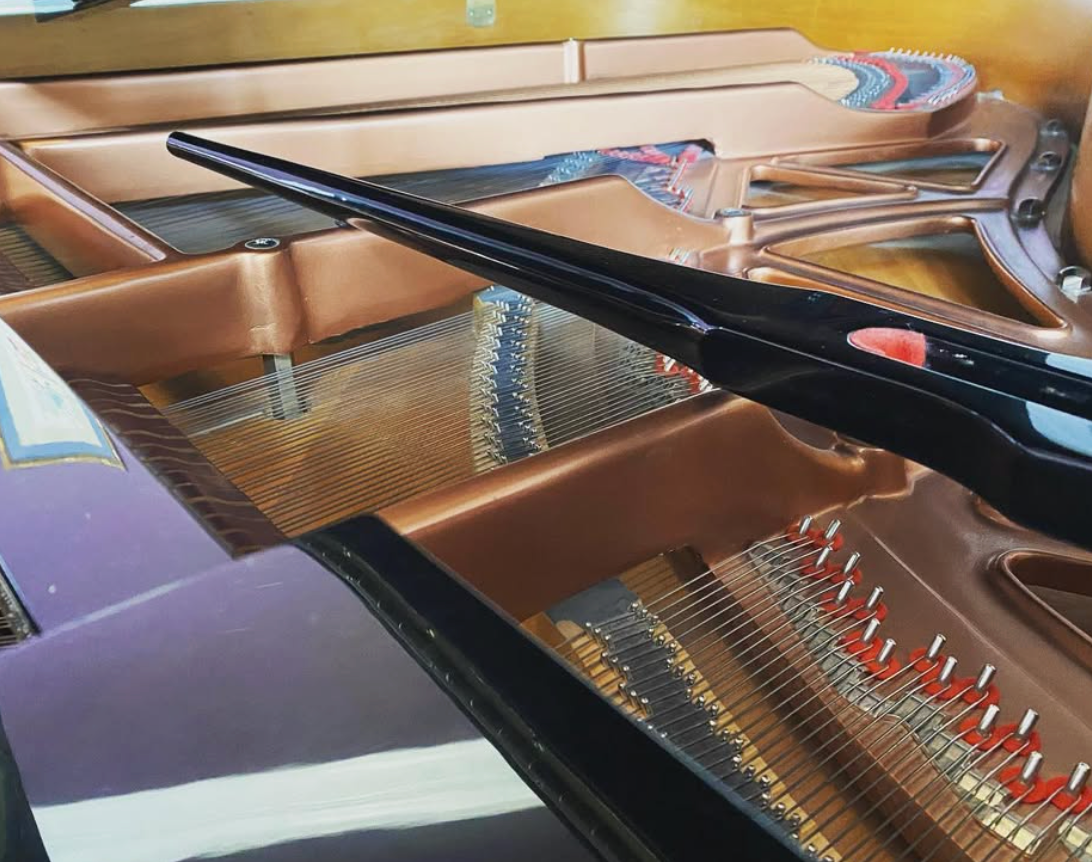Close-up of a grand piano’s strings, hammers, and glossy black frame inside the open lid