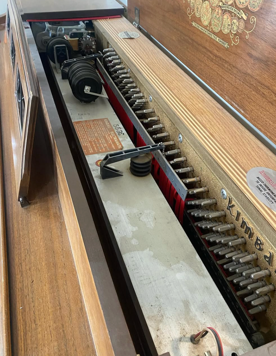 Inside a piano, showing strings, hammers, and action components in a wooden case.
