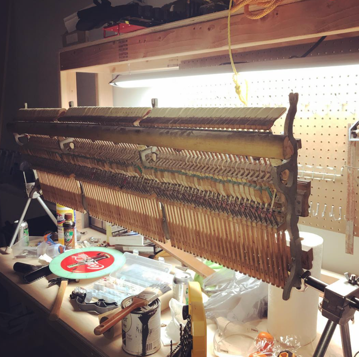 Long, woven textile or loom piece stretched across a workbench in a dim workshop