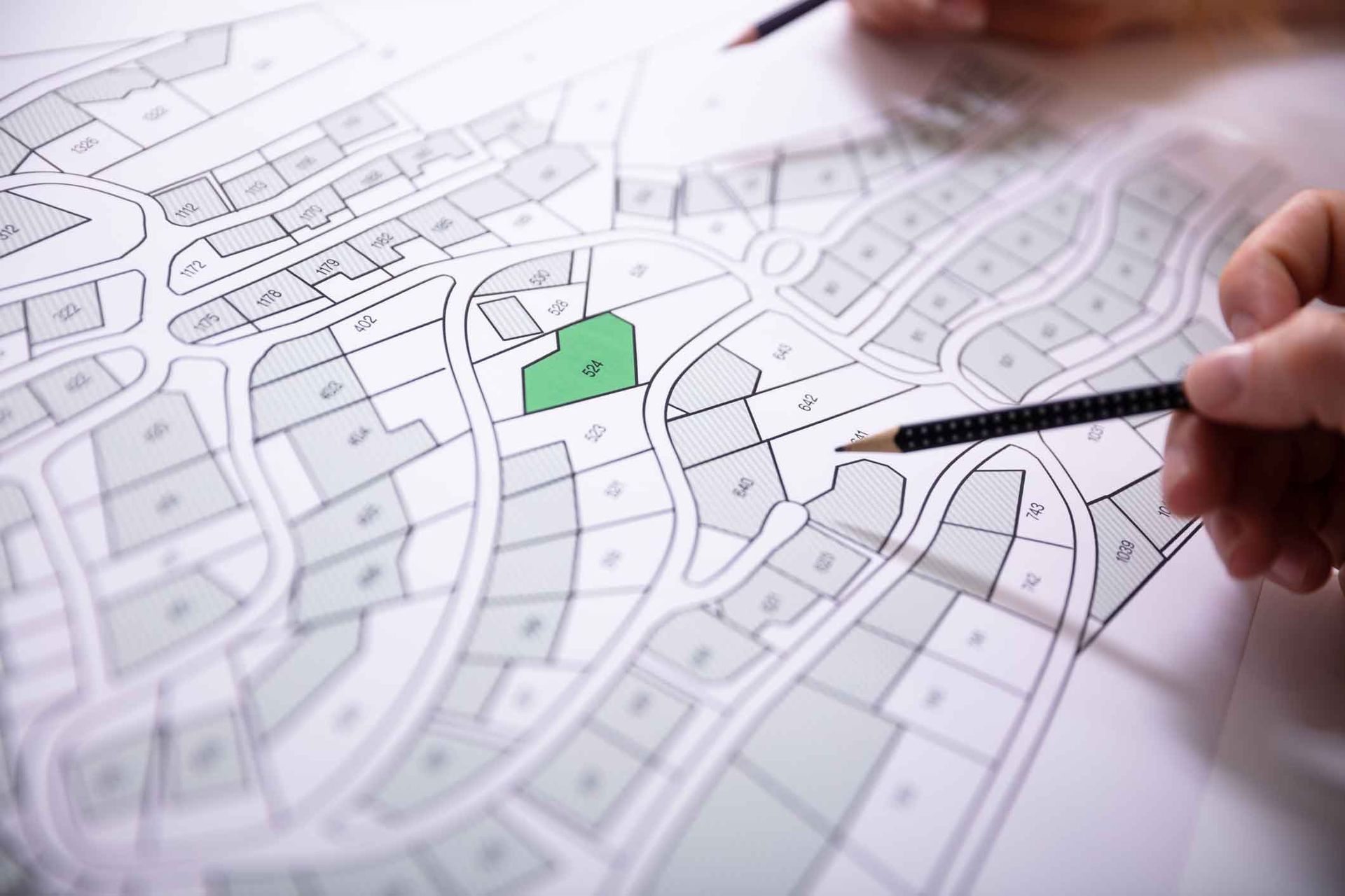 A person is pointing at a green area on a map with a pencil.