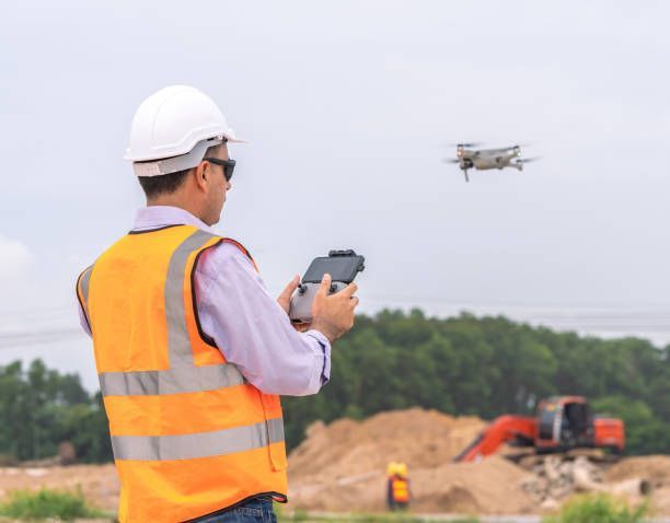 A construction worker is using a remote control to control a drone.