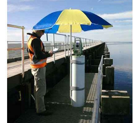 A man is standing on a pier with a blue and yellow umbrella.