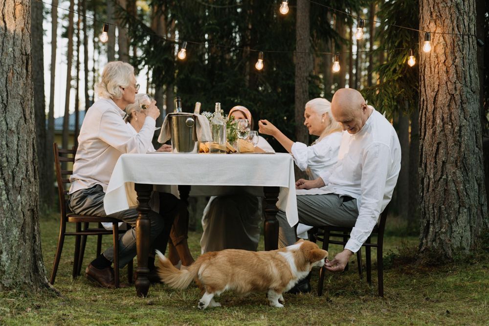 A group of people are sitting at a table with a dog.