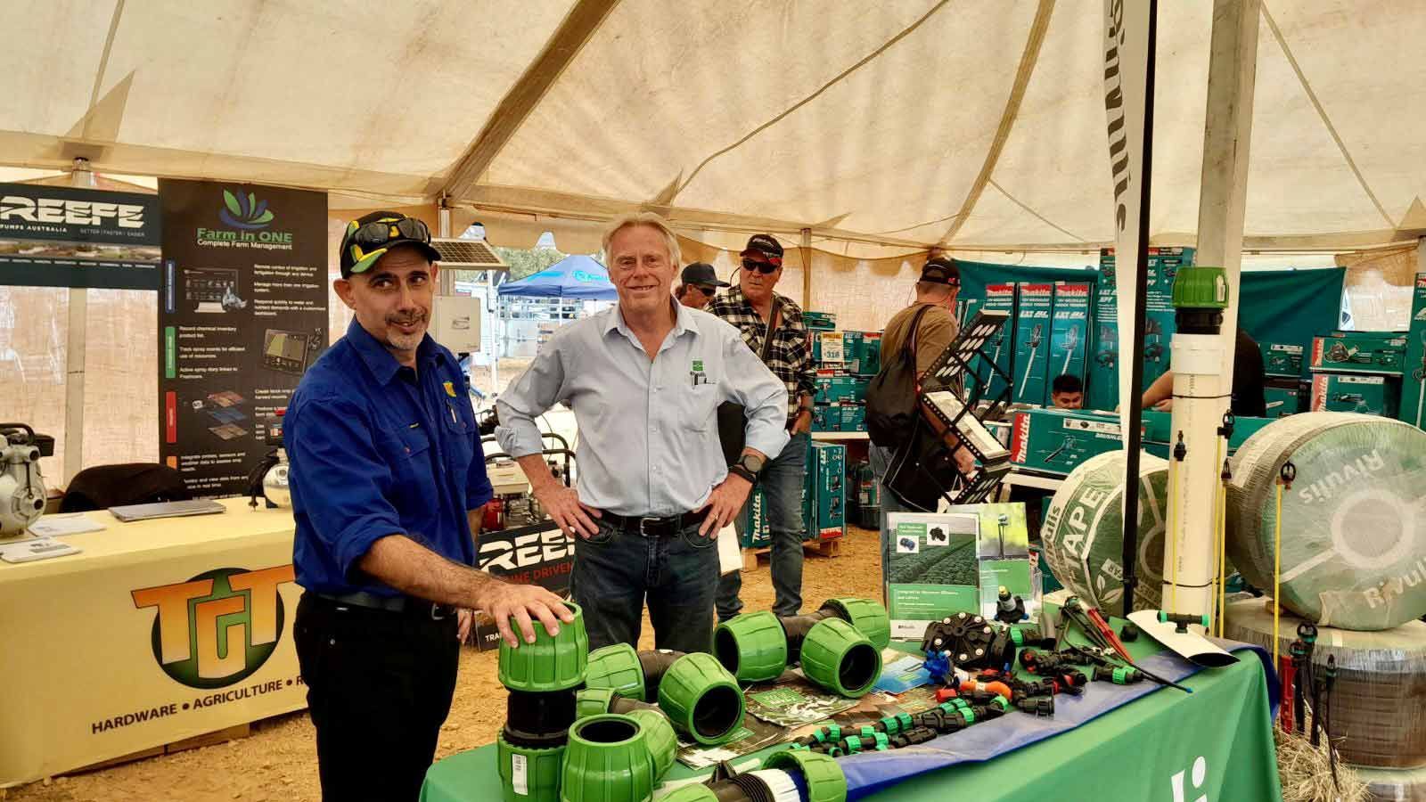 Two Men Are Standing In Front Of A Table With Green Pipes On It — TGT Pty Ltd in Mareeba, QLD