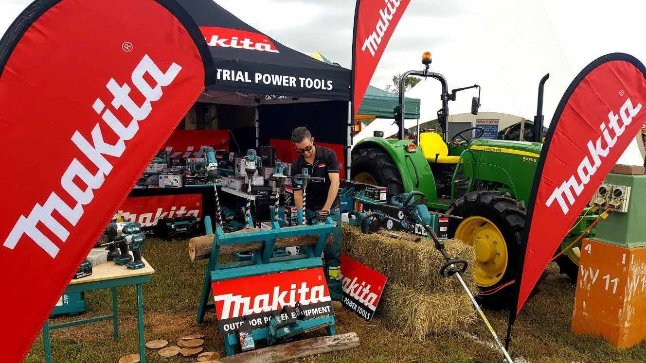 A Man is Working on a Tractor at a Makita Booth — TGT Pty Ltd in Mareeba, QLD
