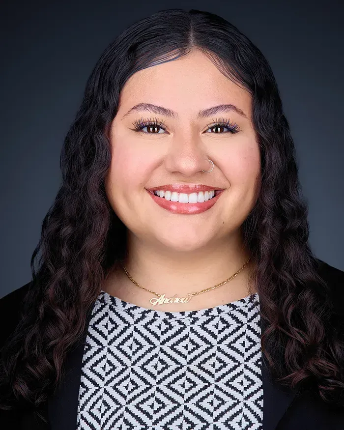 A woman with long curly hair is smiling for the camera.