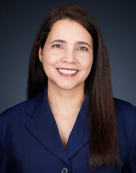 A woman in a blue jacket is smiling for the camera.