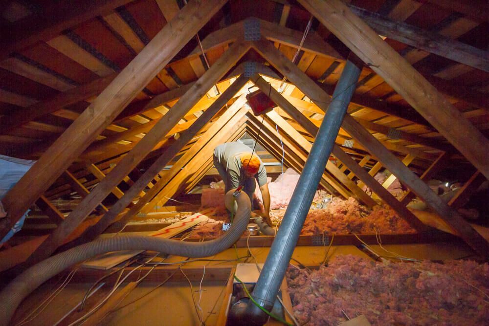 A woman is blowing insulation into the attic of a house.