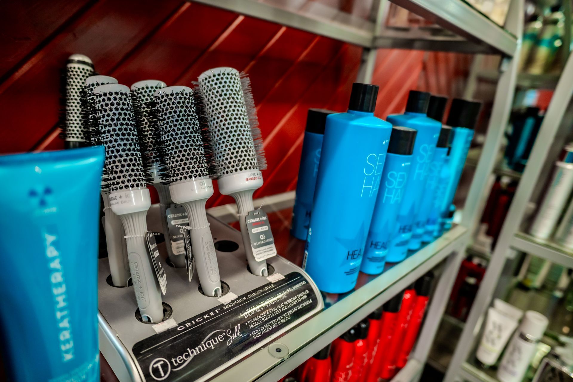 Hair salon display: brushes and blue shampoo bottles on a shelf against a red backdrop.