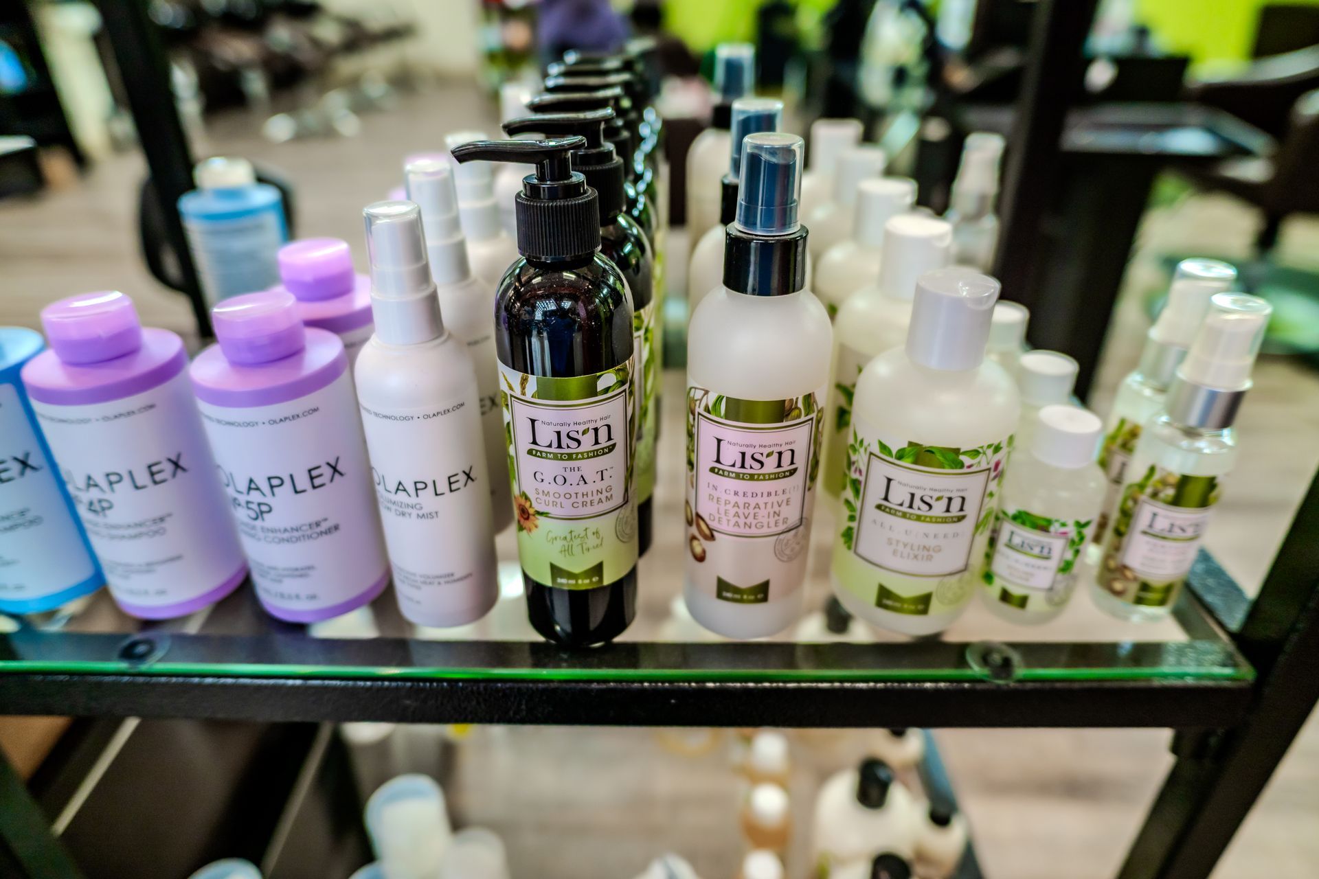Shelf display of various hair care products in a salon. Bottles are in rows, many with pumps.