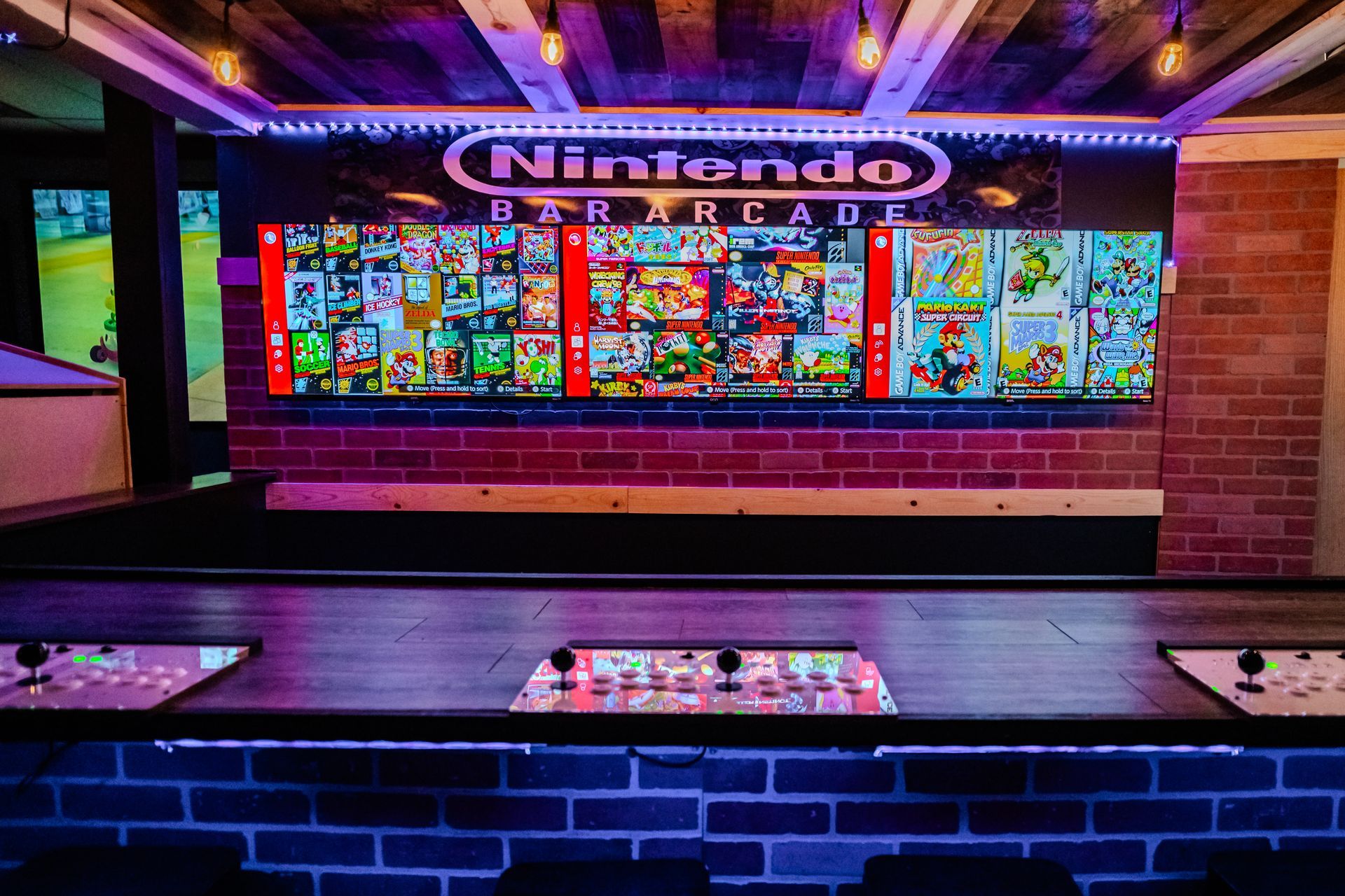 Arcade bar with Nintendo logo, lit brick wall, and retro arcade game controllers on the bar.