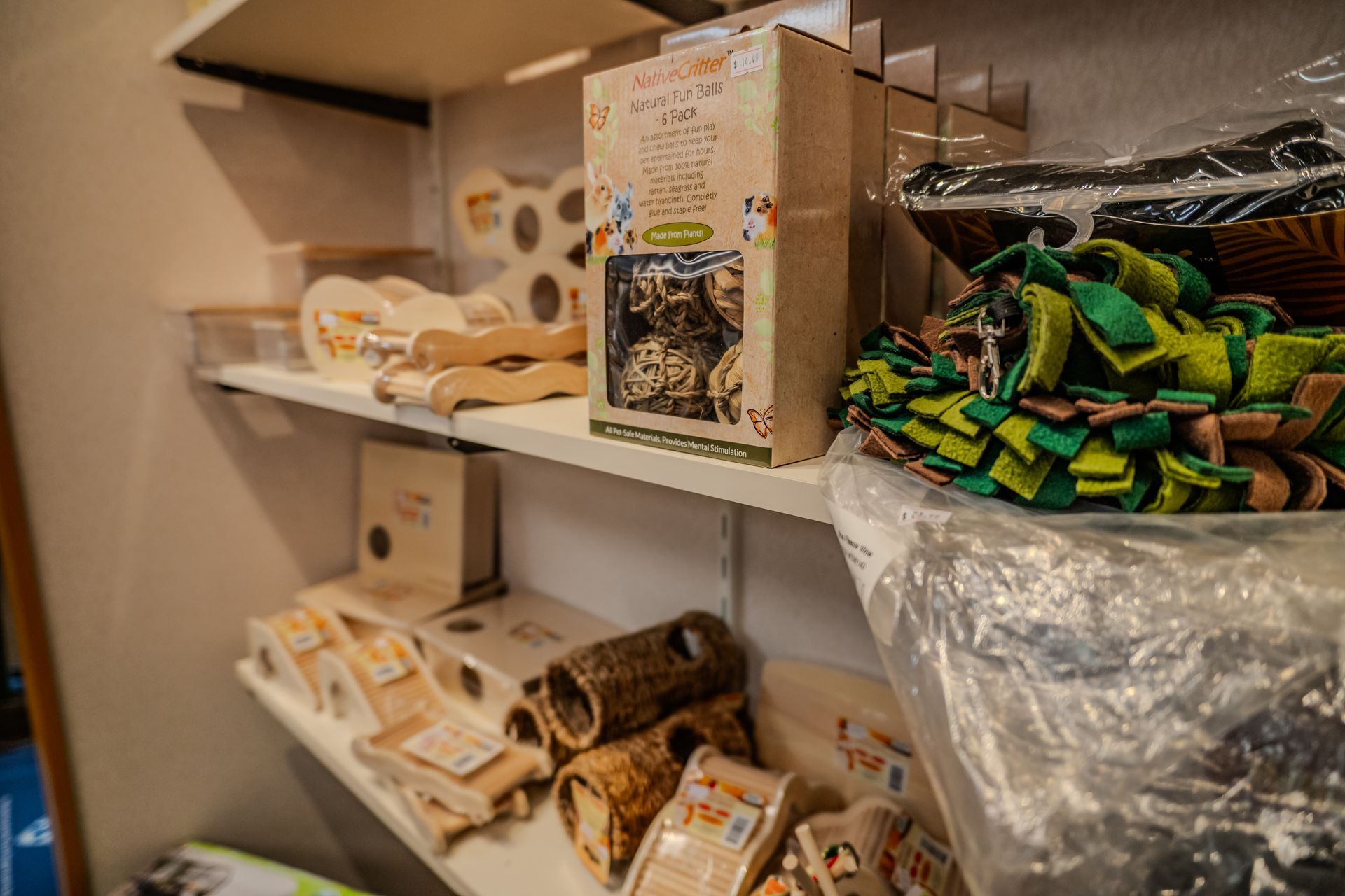 Shelves in a pet store displaying various animal toys, treats, and accessories in a neutral-toned setting.