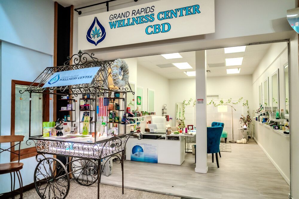 Grand Rapids Wellness Center CBD shop entrance with display cart, sign, and products inside.