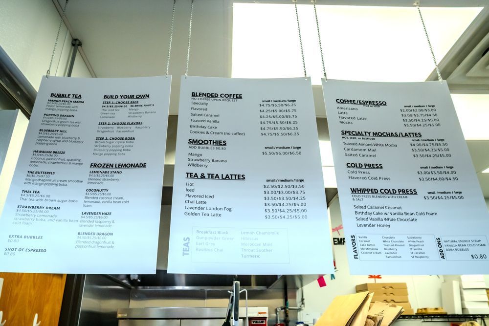 Three hanging menu signs with food and drink options in a restaurant kitchen.