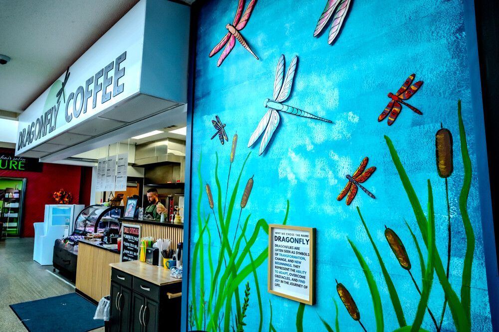 Coffee shop interior: dragonfly mural on blue wall, counter, sign reading 