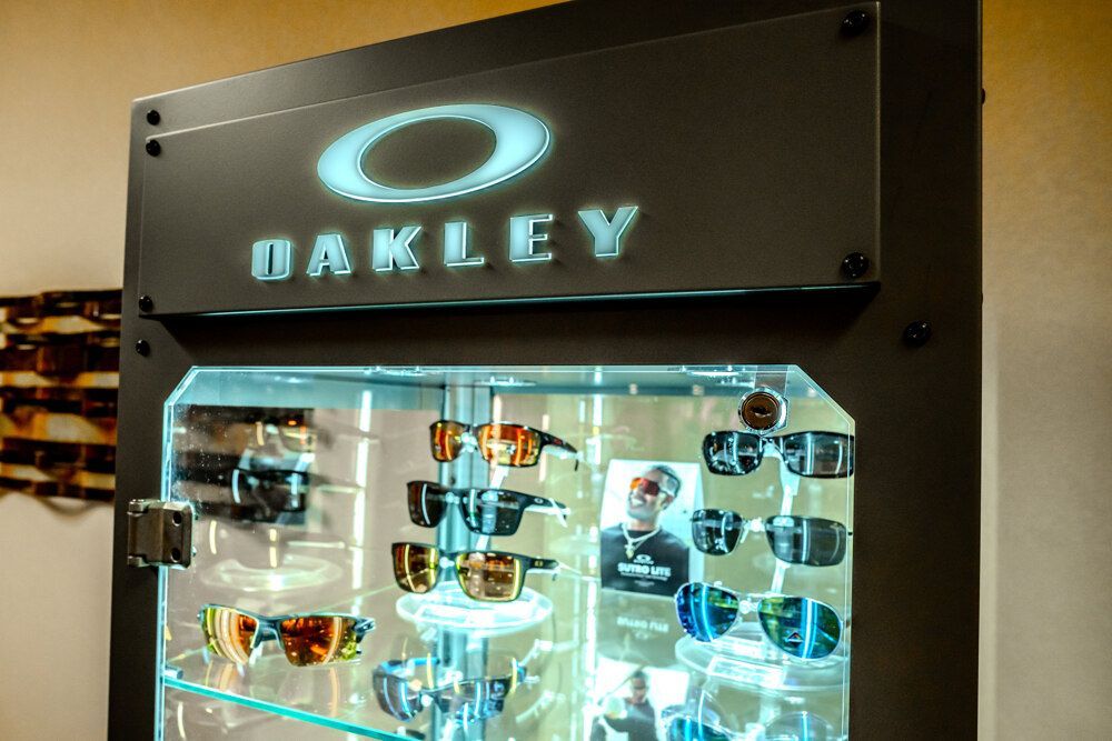 Oakley sunglasses display case with backlit logo, showcasing various eyewear styles.