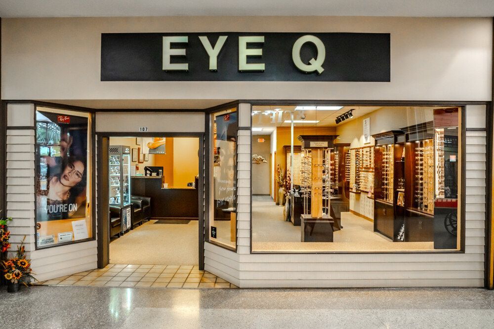 Eye Q optical store front, eyeglasses displayed, open doorway, neutral colors.
