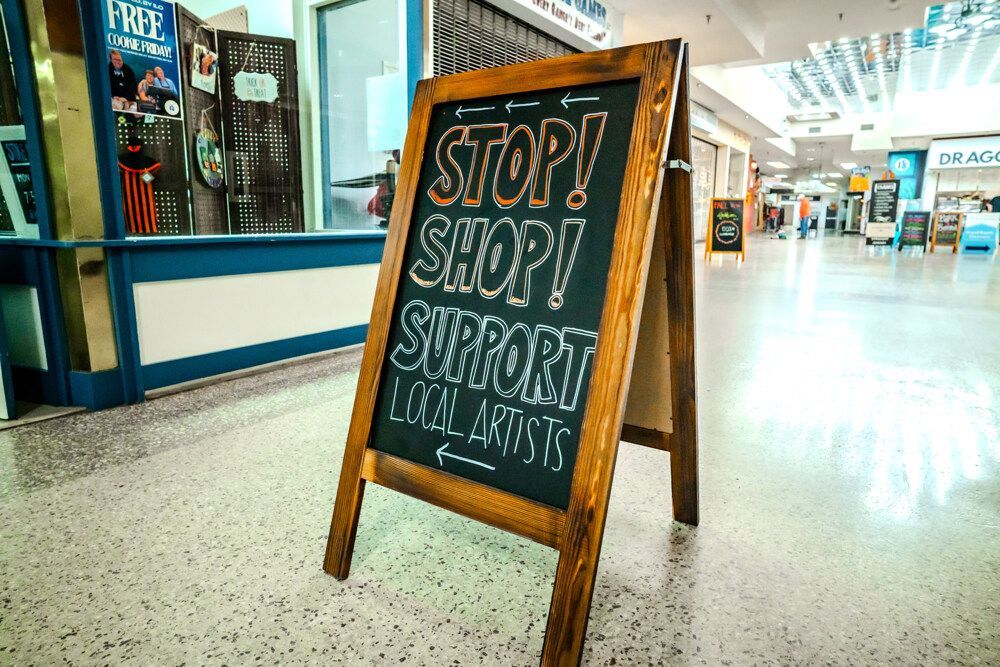Wooden A-frame sign in mall, text reads: 