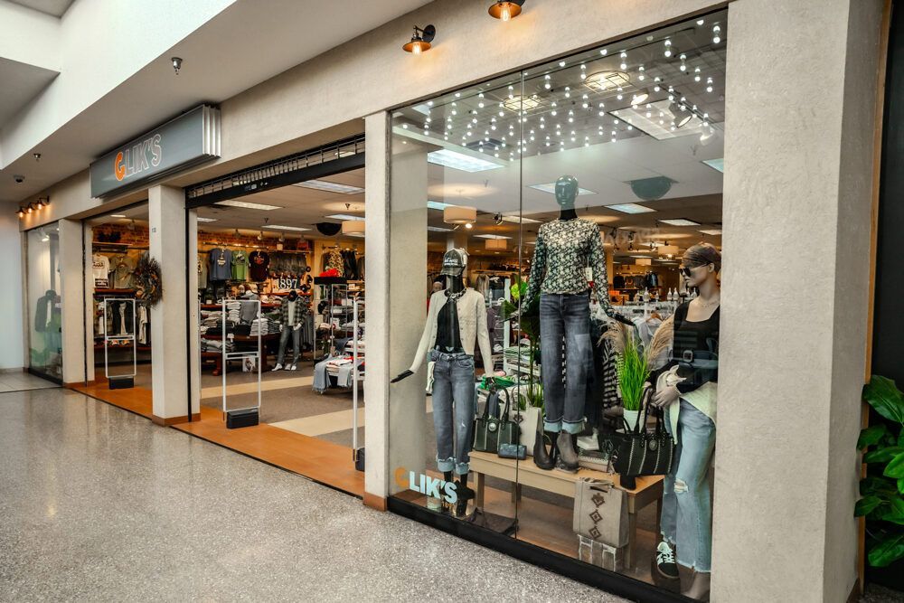Clothing store storefront with mannequins in window display; mall interior.