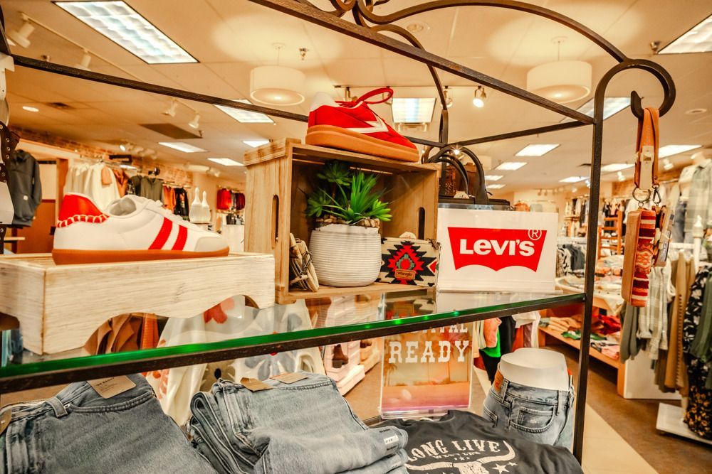 Clothing store interior with display shelves of shoes, jeans, and Levi's sign.