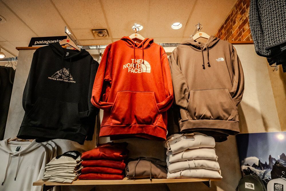 Hooded sweatshirts in black, red, and brown hanging on display in a store.