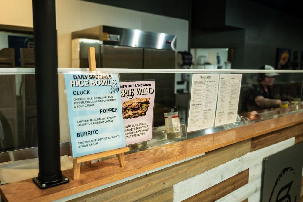 Counter with menu signs. A person prepares food behind the counter.