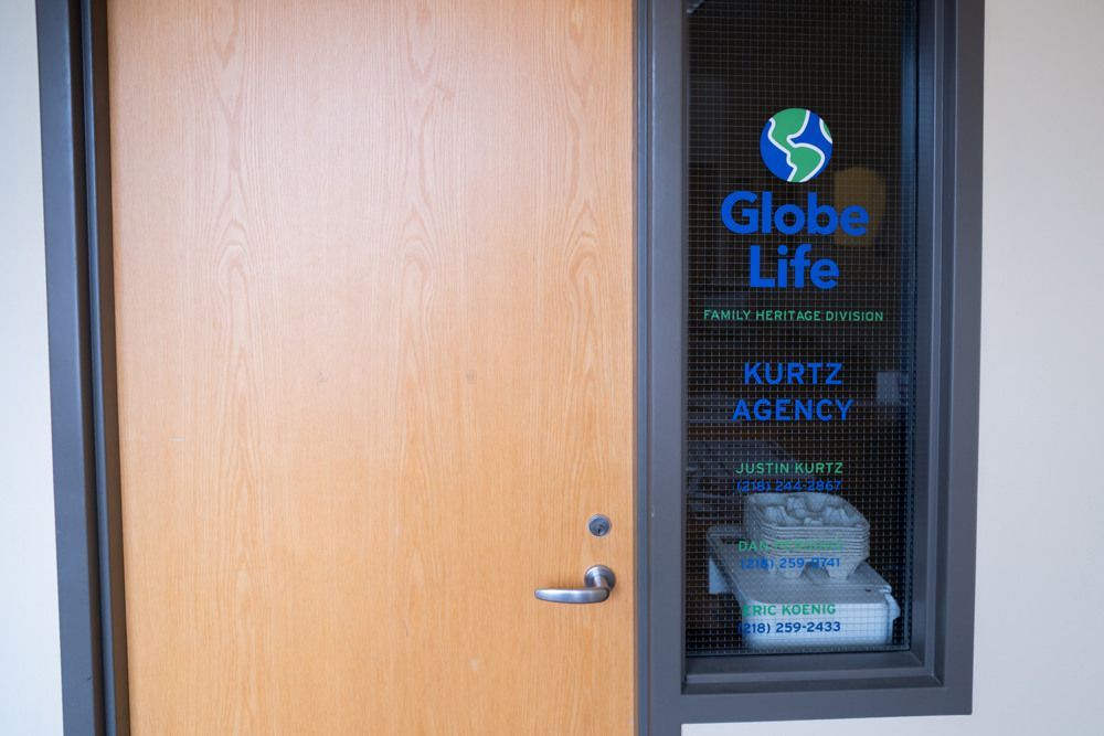 A light wood door with a window featuring a Globe Life logo and 