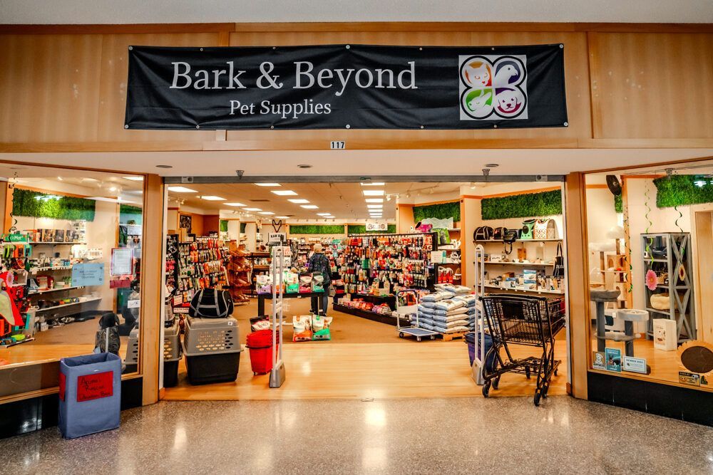 Bark & Beyond pet supply store entrance; open door reveals store interior with products on shelves and customers shopping.