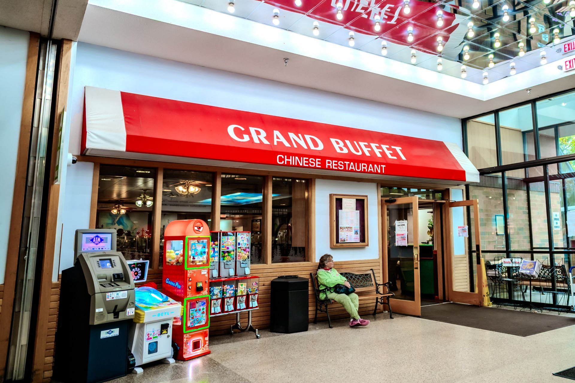 Grand Buffet Chinese Restaurant with red awning. Person sits outside; arcade games nearby.