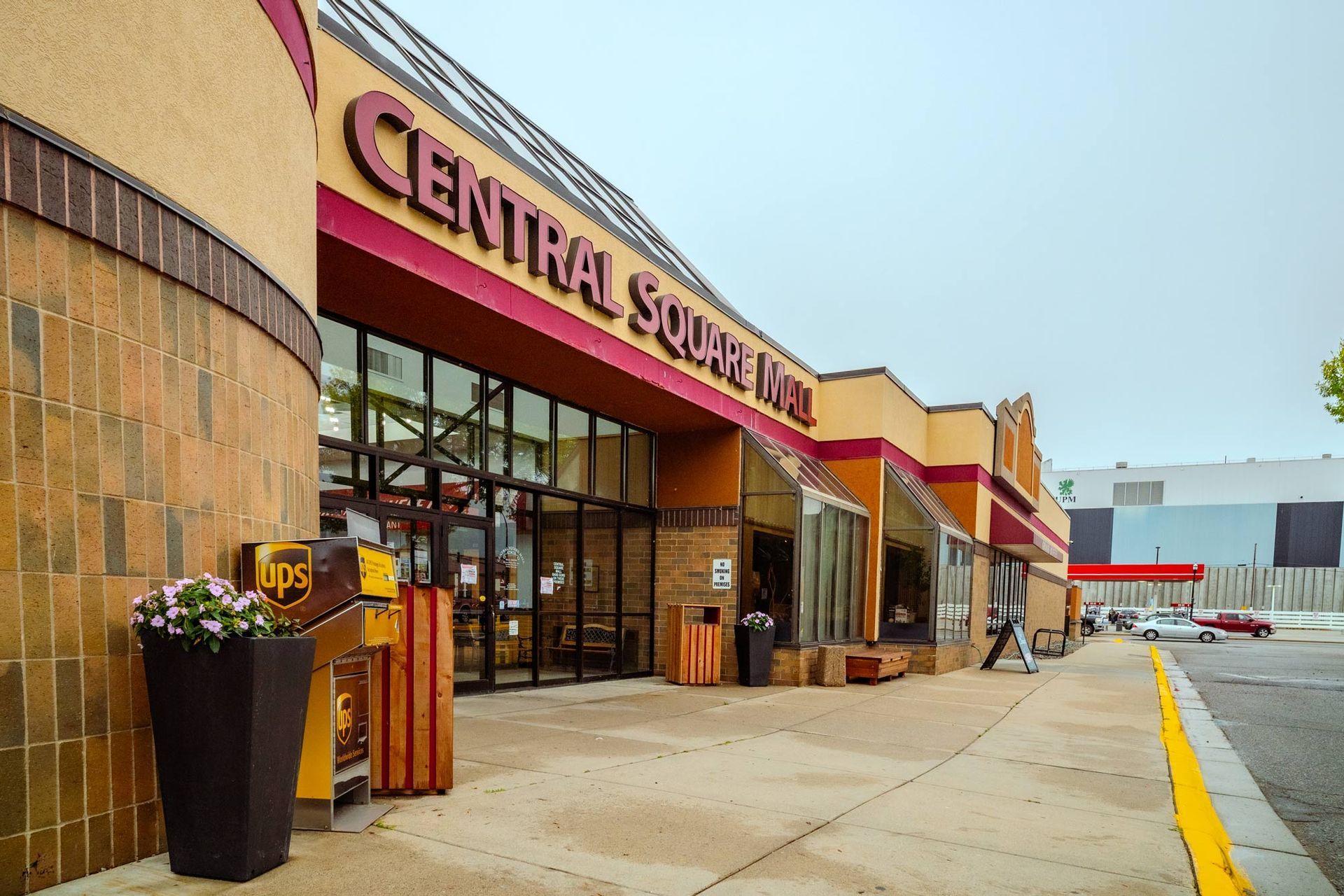 Central Square Mall entrance with tan and red exterior, glass windows, and a flower pot.