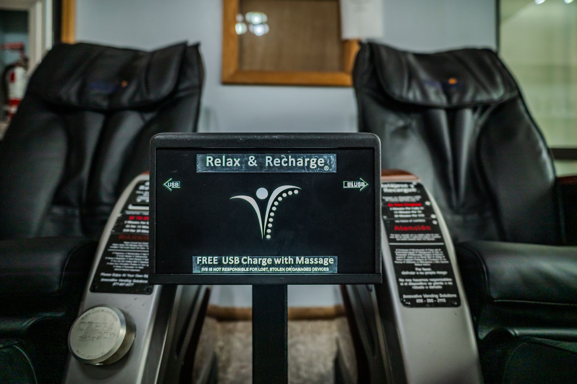 Two black massage chairs with a control panel that says, 