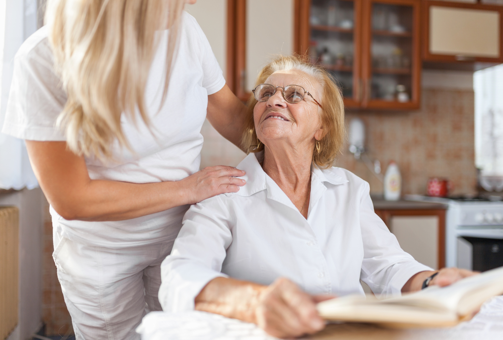 Person's hands held by another, possibly in a caregiving setting, offering comfort and support.