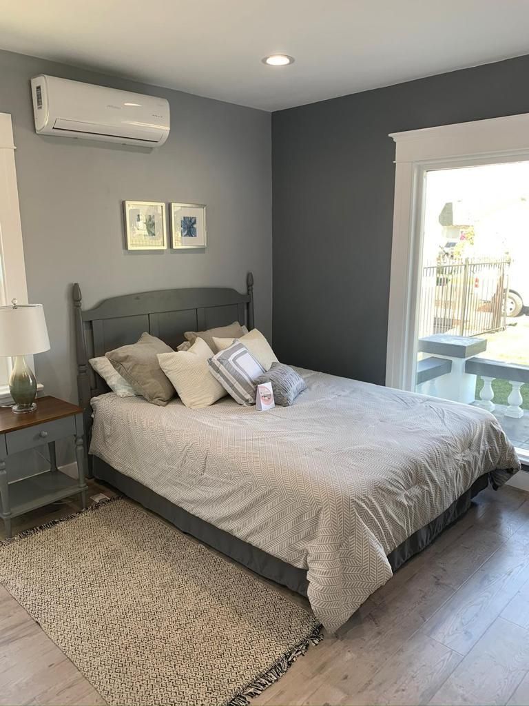 A bedroom with a bed , nightstand , rug and window.