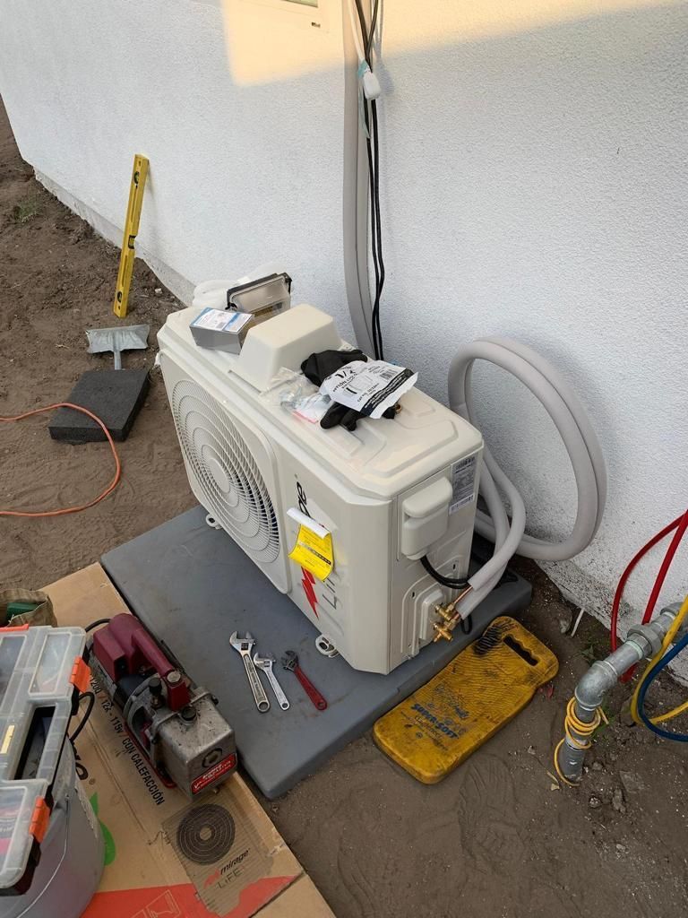 A white air conditioner is sitting on top of a cardboard box.