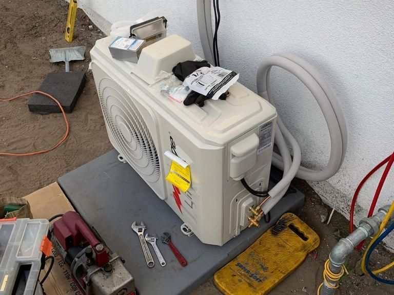 A white air conditioner is sitting on a table next to tools.